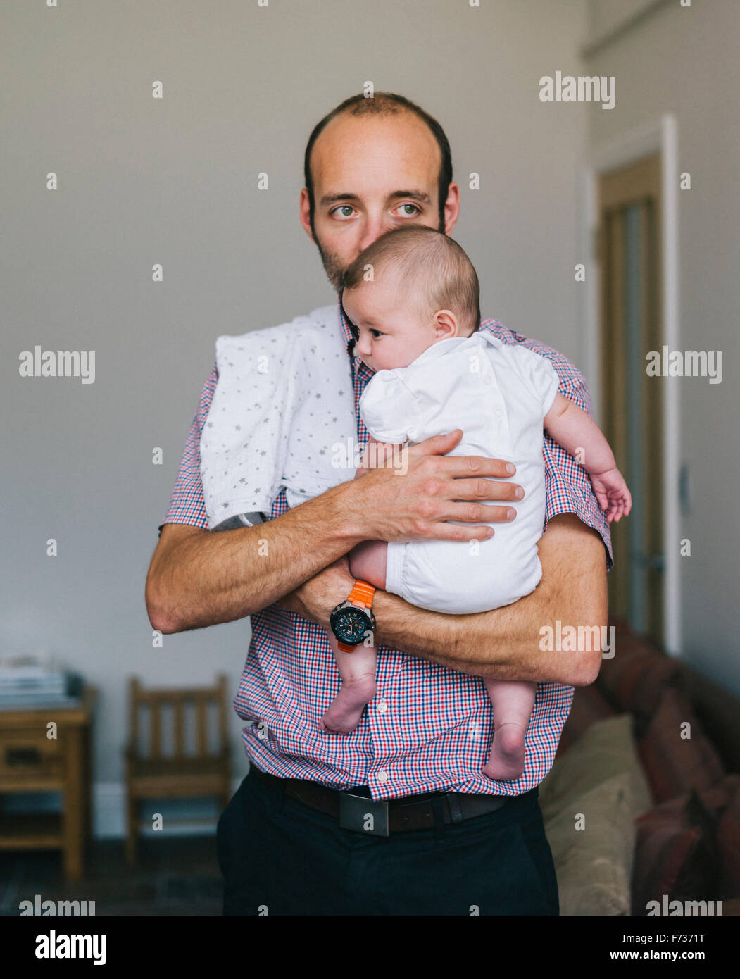 Ein Mann hält ein junges Baby an seine Brust. Stockfoto