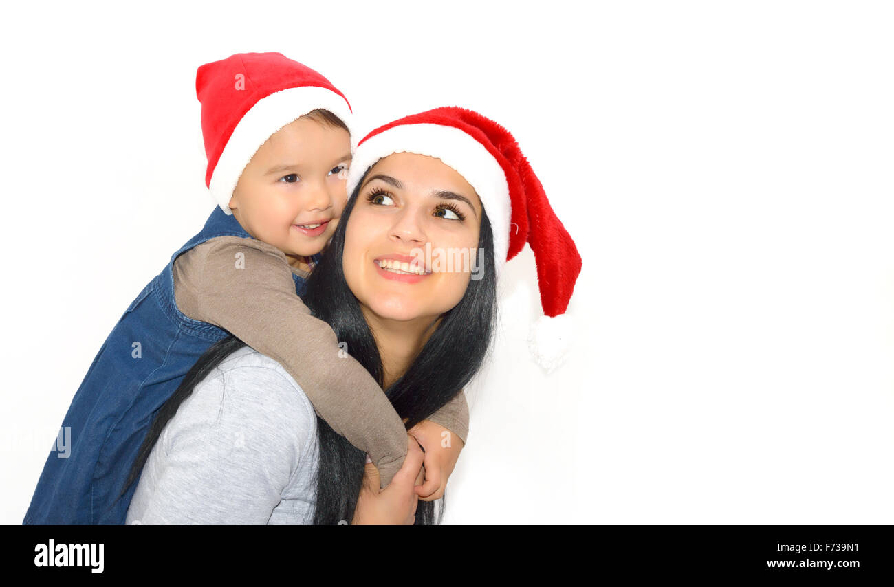 Weihnachten, Familie, Kindheit und Menschen Konzept - glückliche Mutter und kleine Mädchen in Santa Hüte über Feiertage isoliert auf weiss Stockfoto