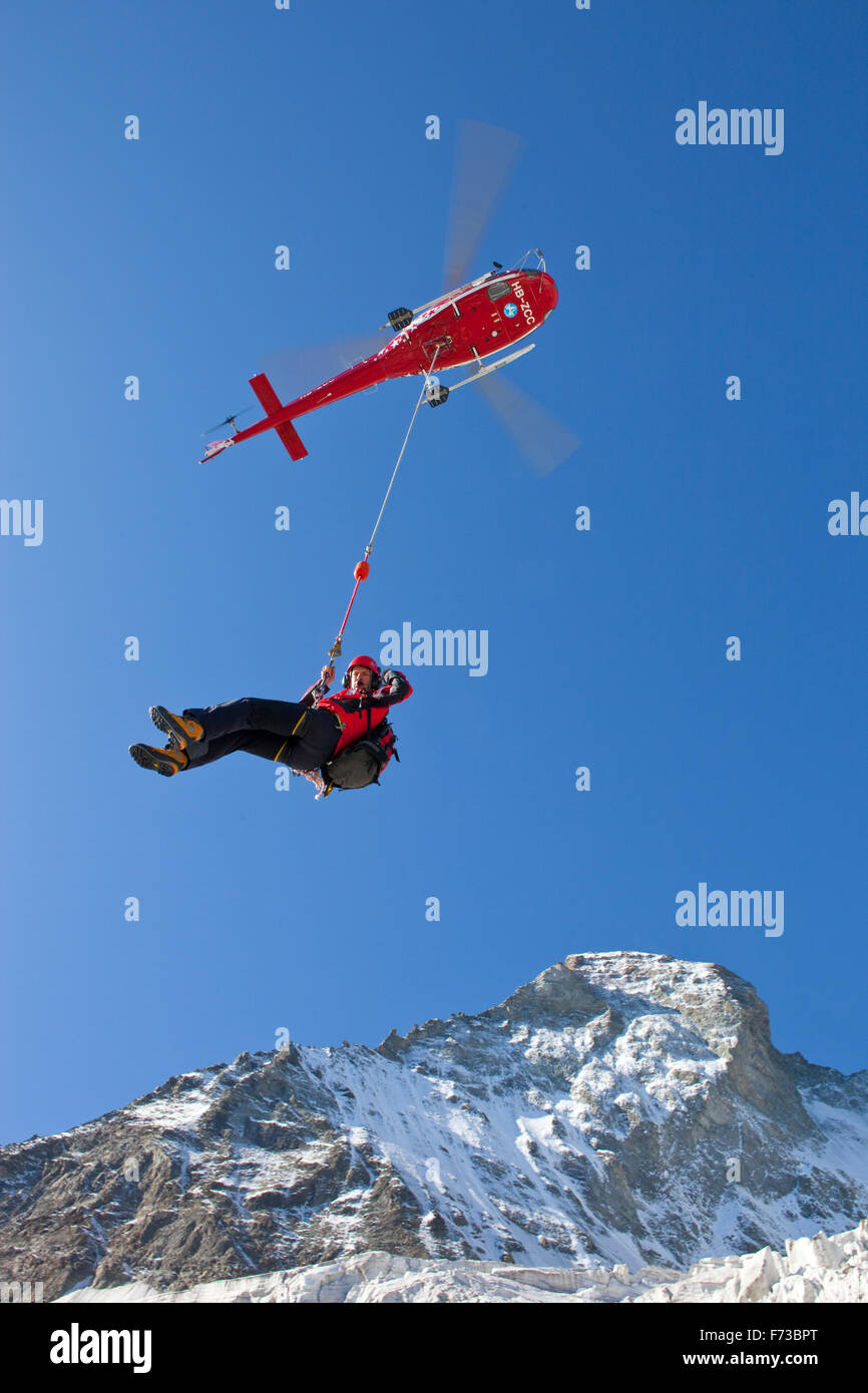 Bergretter hängt an der Longline unter einen Air Zermatt Hubschrauber vor der Matterhorn-Nordwand in den Schweizer Alpen. Stockfoto