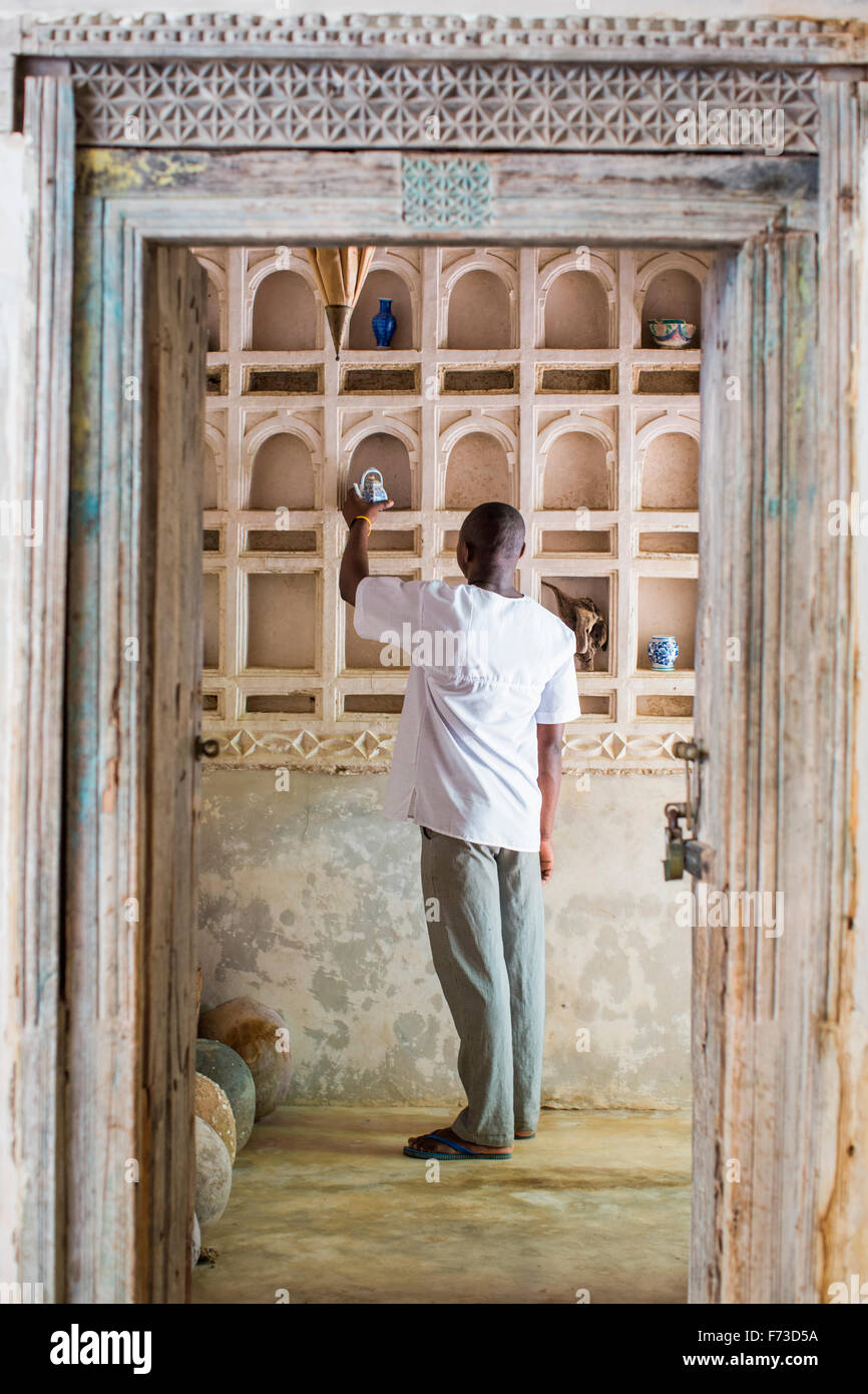 LAMU, KENIA, AFRIKA. Ein Mann in weißes Baumwollshirt stellt Kunst auf  einem Regal in einem historischen Hof Stockfotografie - Alamy