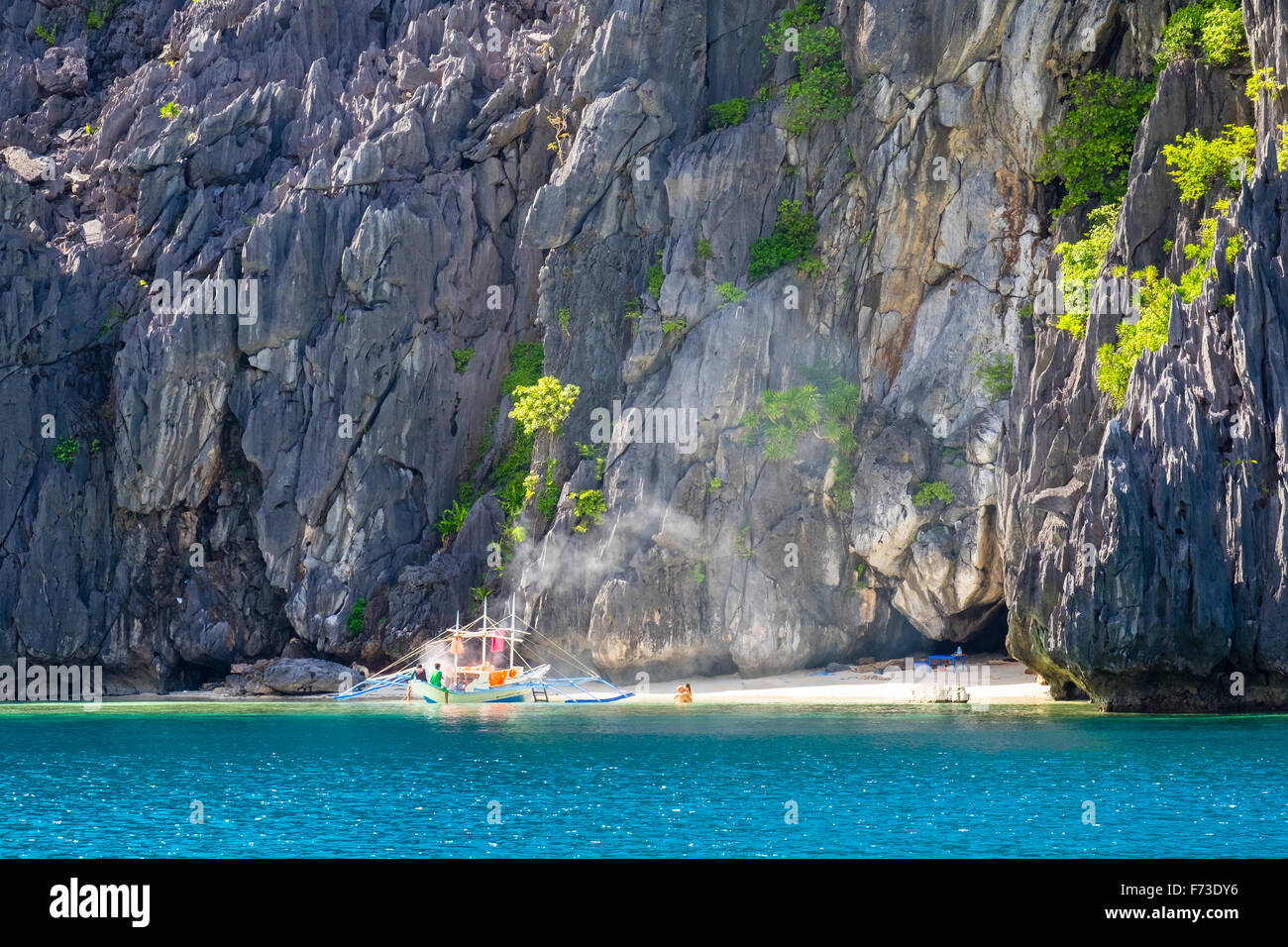 Ein paar umfasst neben einem Ausleger Eber verankert an einem kleinen Strand Stockfoto