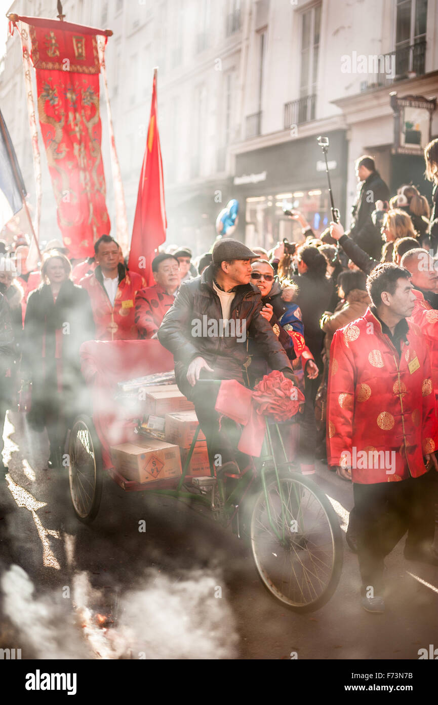 Paris, Frankreich - 2. Februar 2014: Chinesische Künstler auf einem Dreirad in Rauch auf der chinesischen Neujahrsfest-Parade. Stockfoto