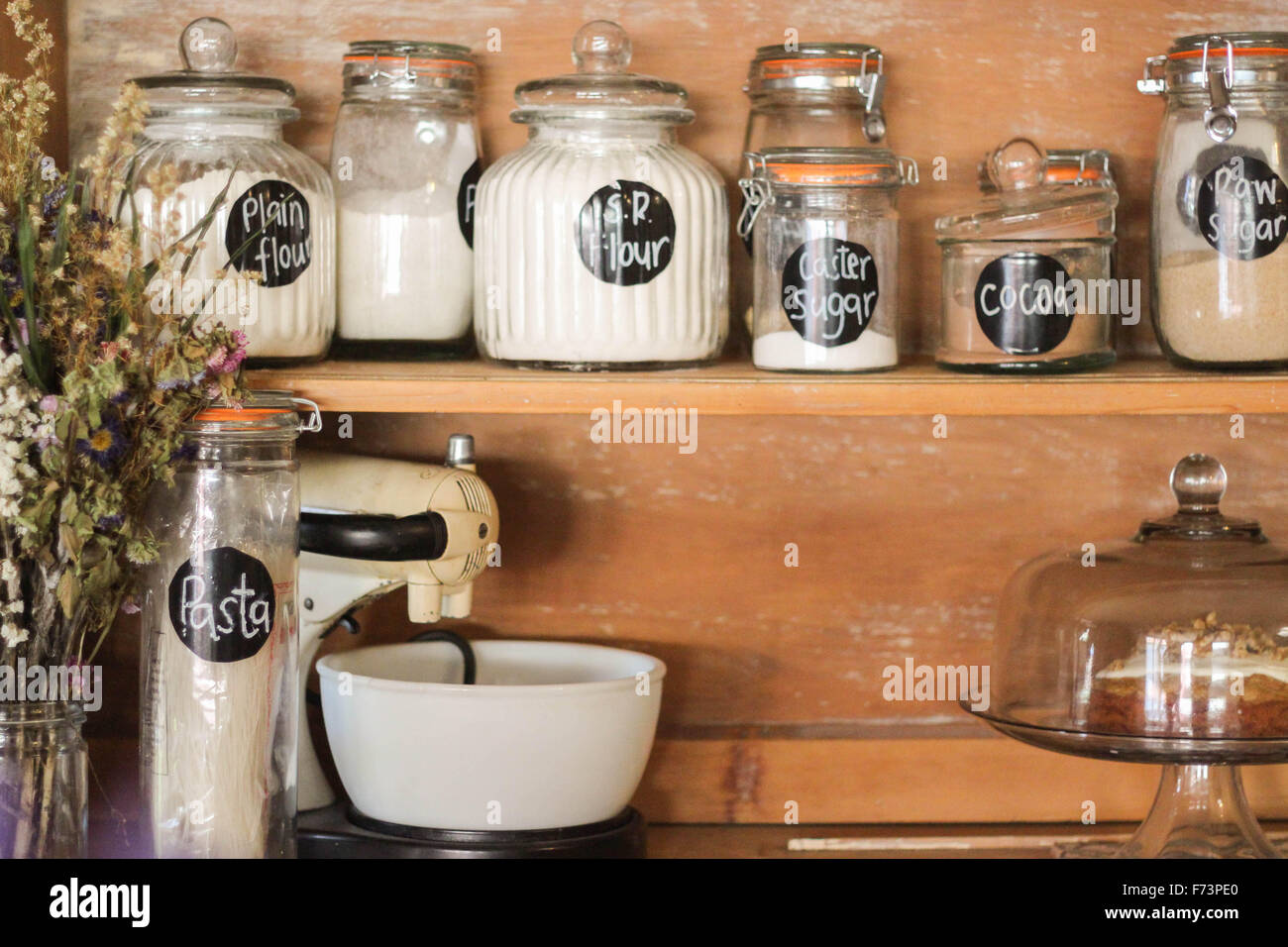 Backzutaten auf eine antike Küche Stall angezeigt. Eine stilvolle Möglichkeit, Ihre Grundnahrungsmittel wie Mehl, Zucker, Nudeln etc. zu speichern. Stockfoto
