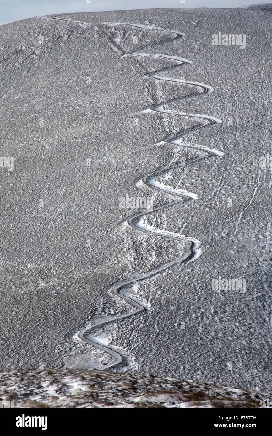 Eine kurvenreiche Zick Zack Weg an der Seite eines kleinen Berges im Winter, mit den Details des Pfades mit Schnee und Eis herausgesucht. Stockfoto