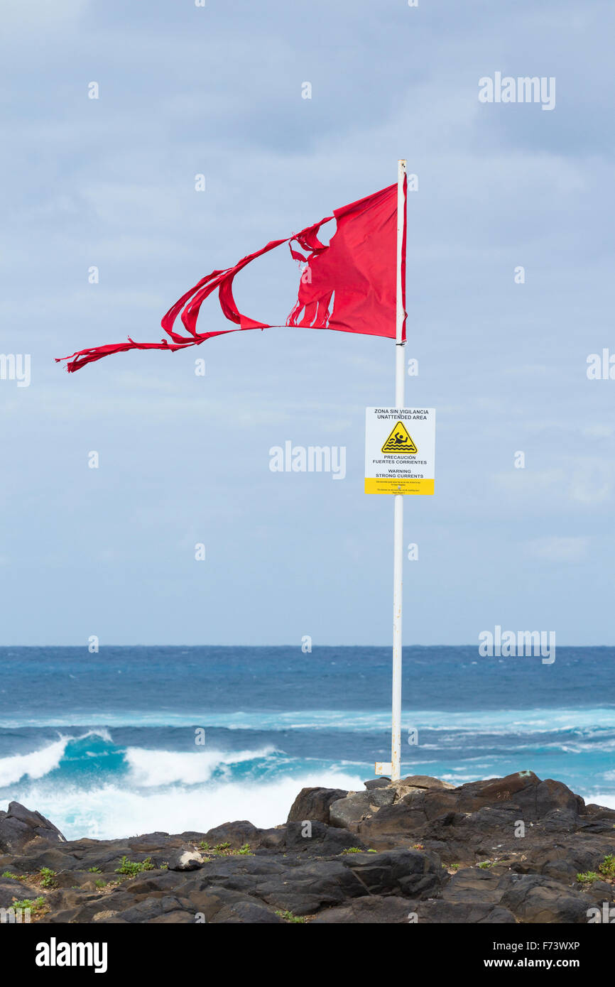 Zerfetzte rote Fahne und starke Strömungen anmelden windiger Strand in Spanien Stockfoto
