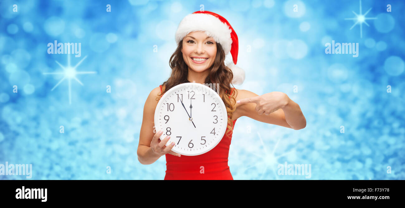 Frau in Helfer Weihnachtsmütze mit Anzeige 12 Uhr Stockfoto