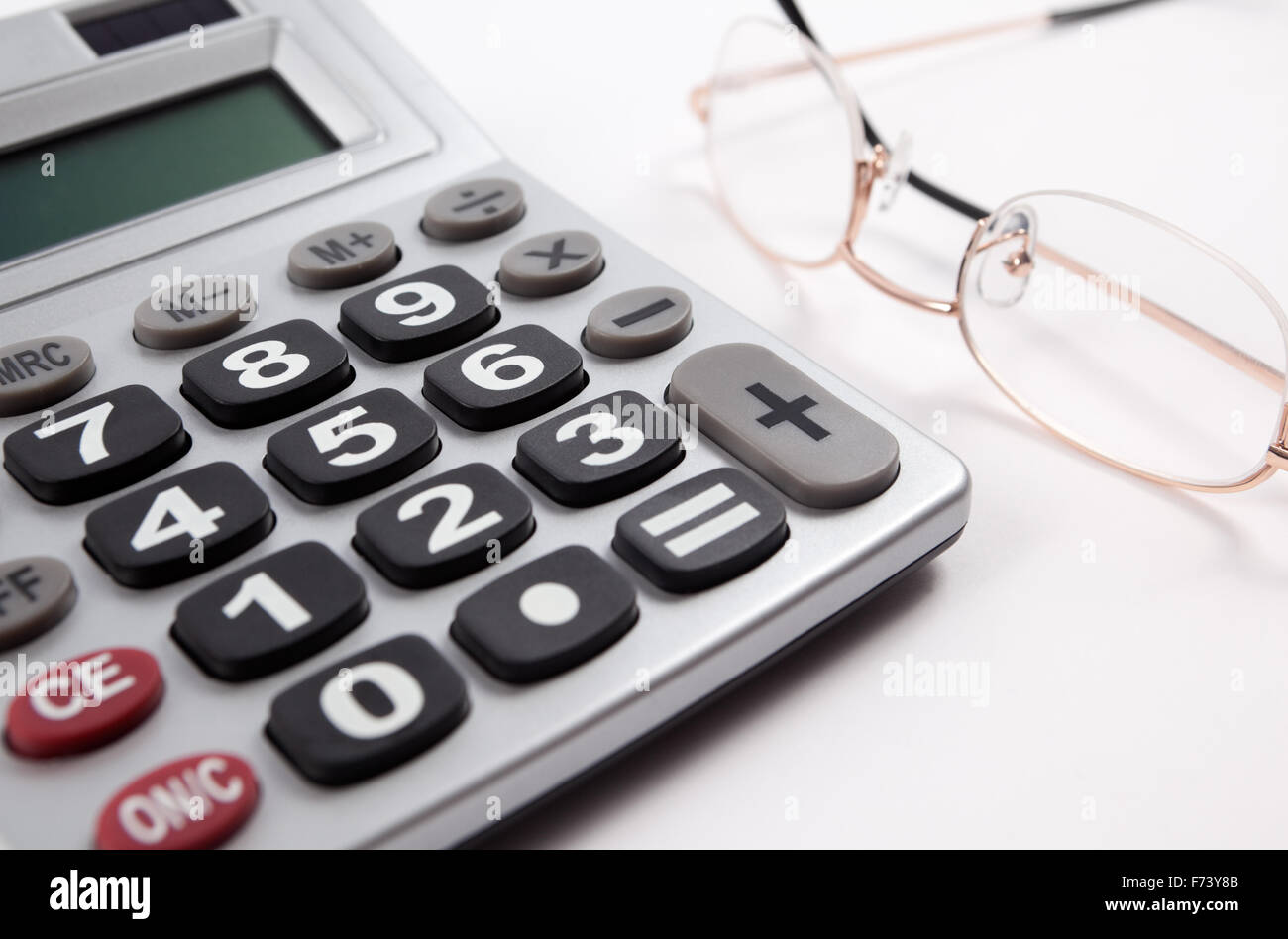 Business-Hintergrund mit Taschenrechner und Gläser isoliert in weiß Stockfoto