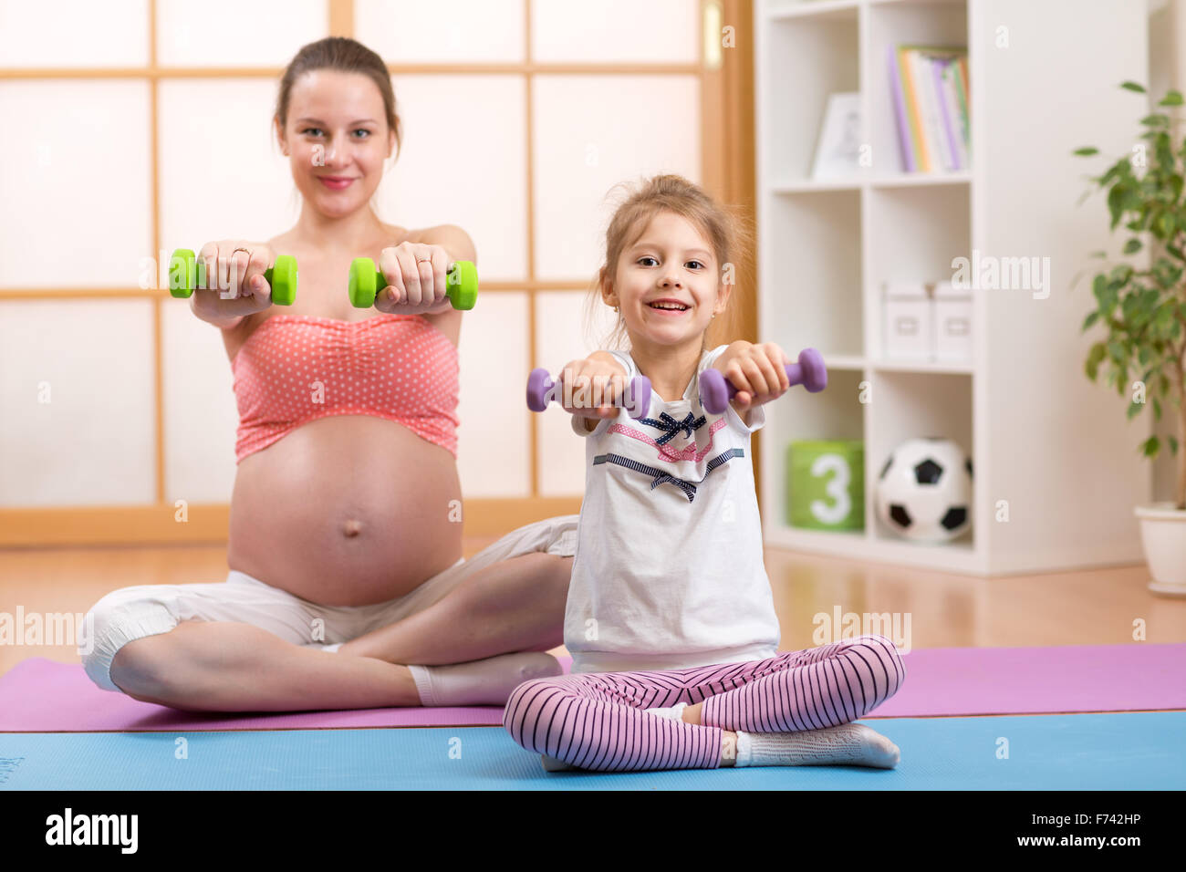 Schwangere Frau mit Kind heben Hanteln trainieren Stockfoto