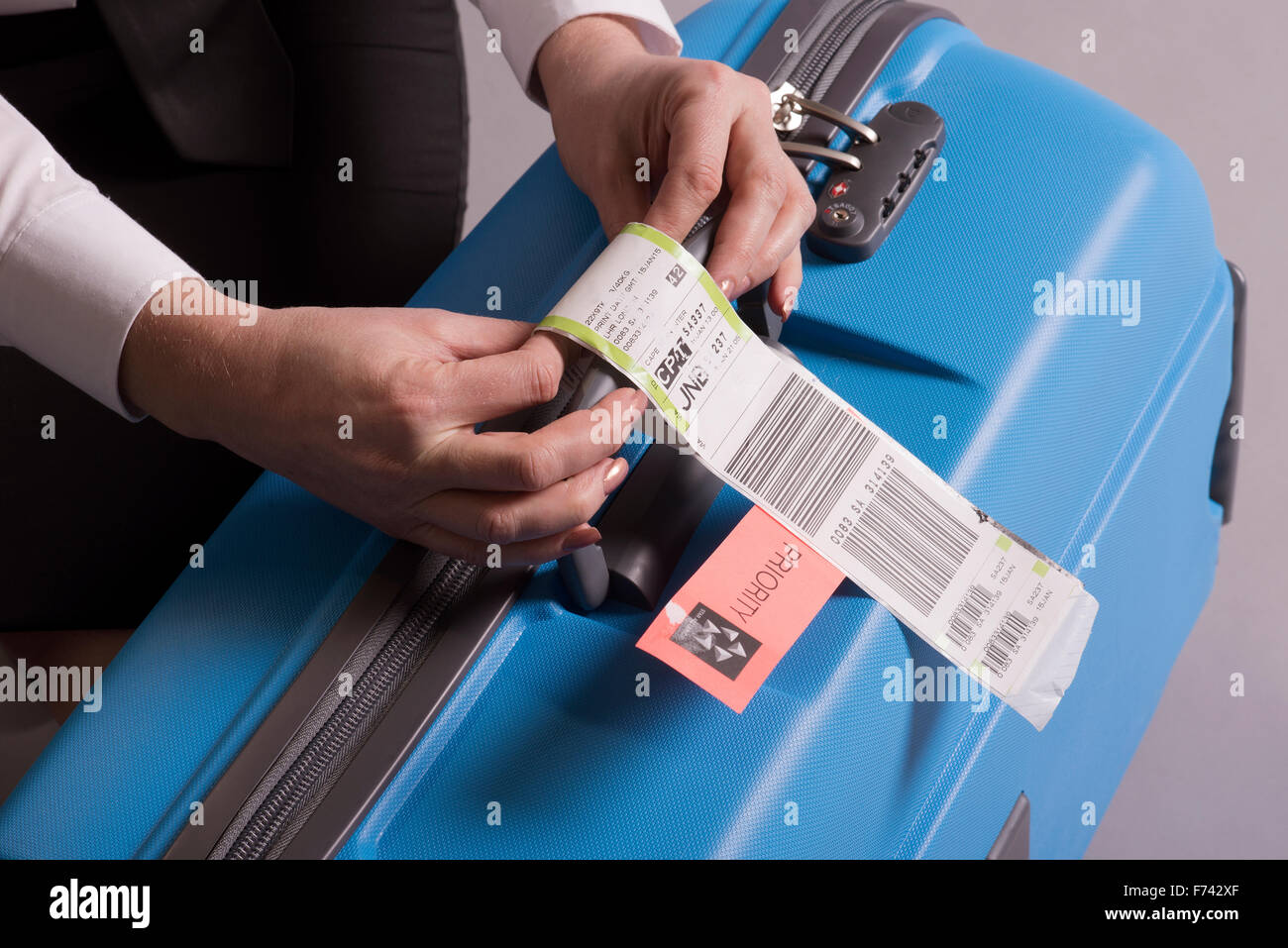 Fluggesellschaft einchecken Gepäckanhänger Anhaftung an einen Koffer. Priorität Tags Fluggepäck Stockfoto