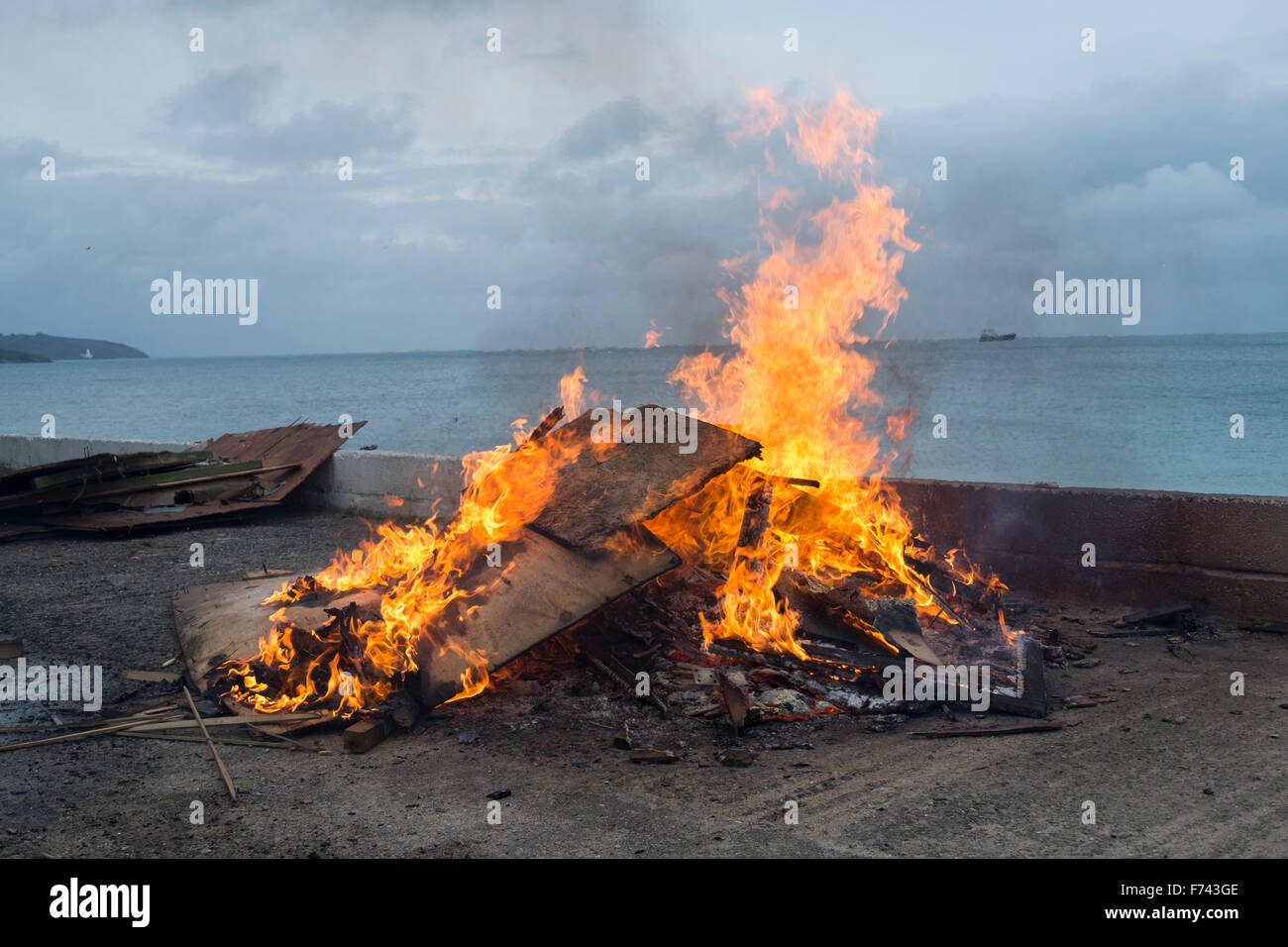 Ein Lagerfeuer an der Seite des Gylly Beach Cafe, Falmouth Cornwall wie sie Holz und andere Abfälle verbrennen Stockfoto