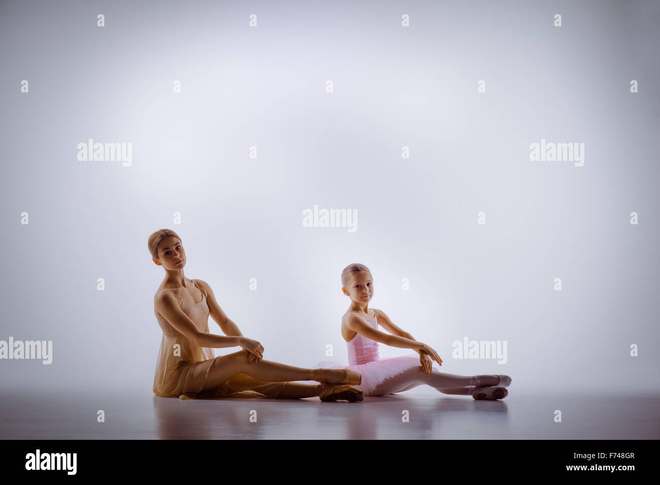 Die kleine Ballerina im Tutu mit persönlichen klassische Ballettlehrerin posiert zusammen auf einem weißen Tanz-Studio-Hintergrund Stockfoto