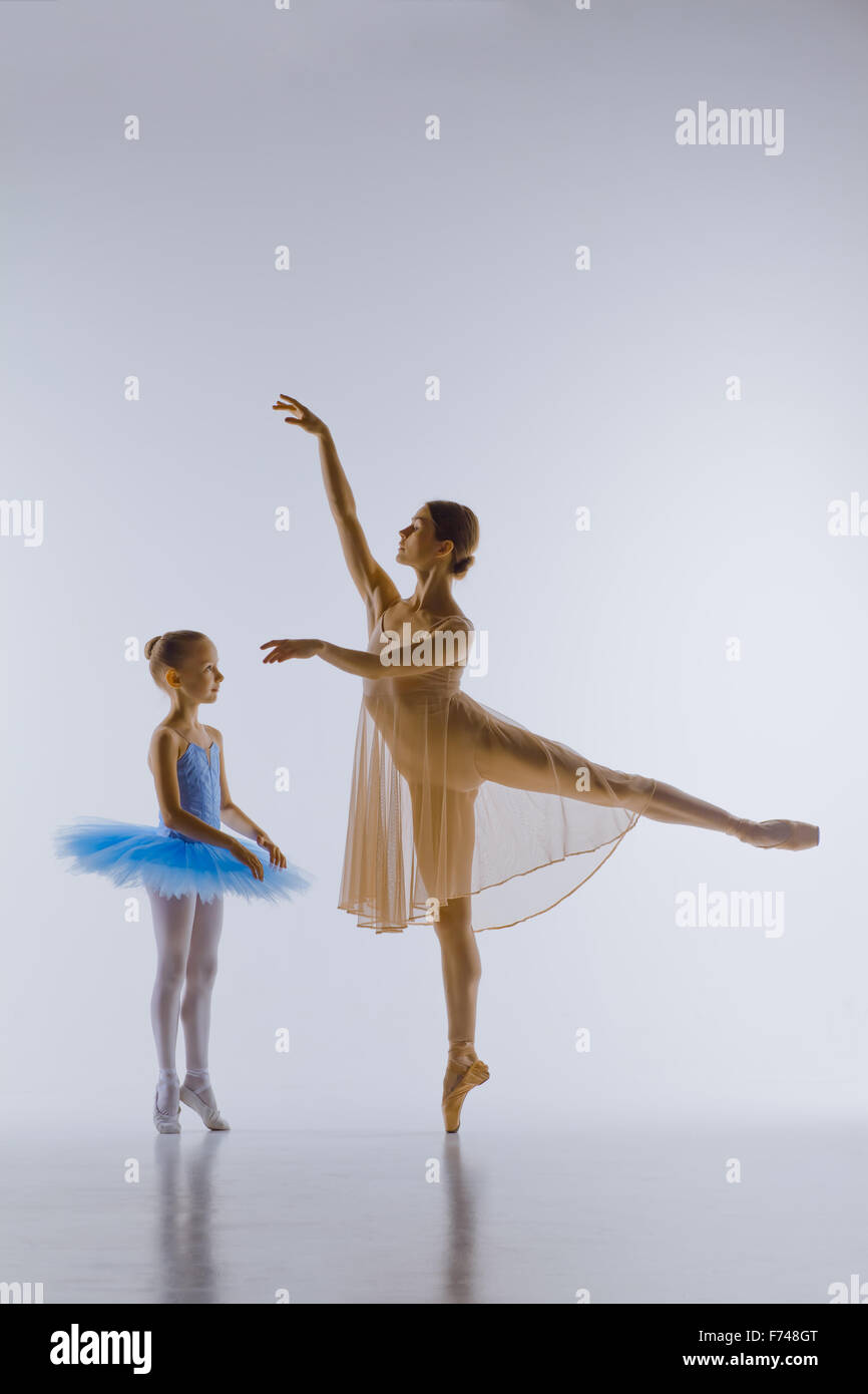 Die kleine Ballerina im Tutu mit persönlichen klassische Ballettlehrerin posiert zusammen auf einem weißen Tanz-Studio-Hintergrund Stockfoto