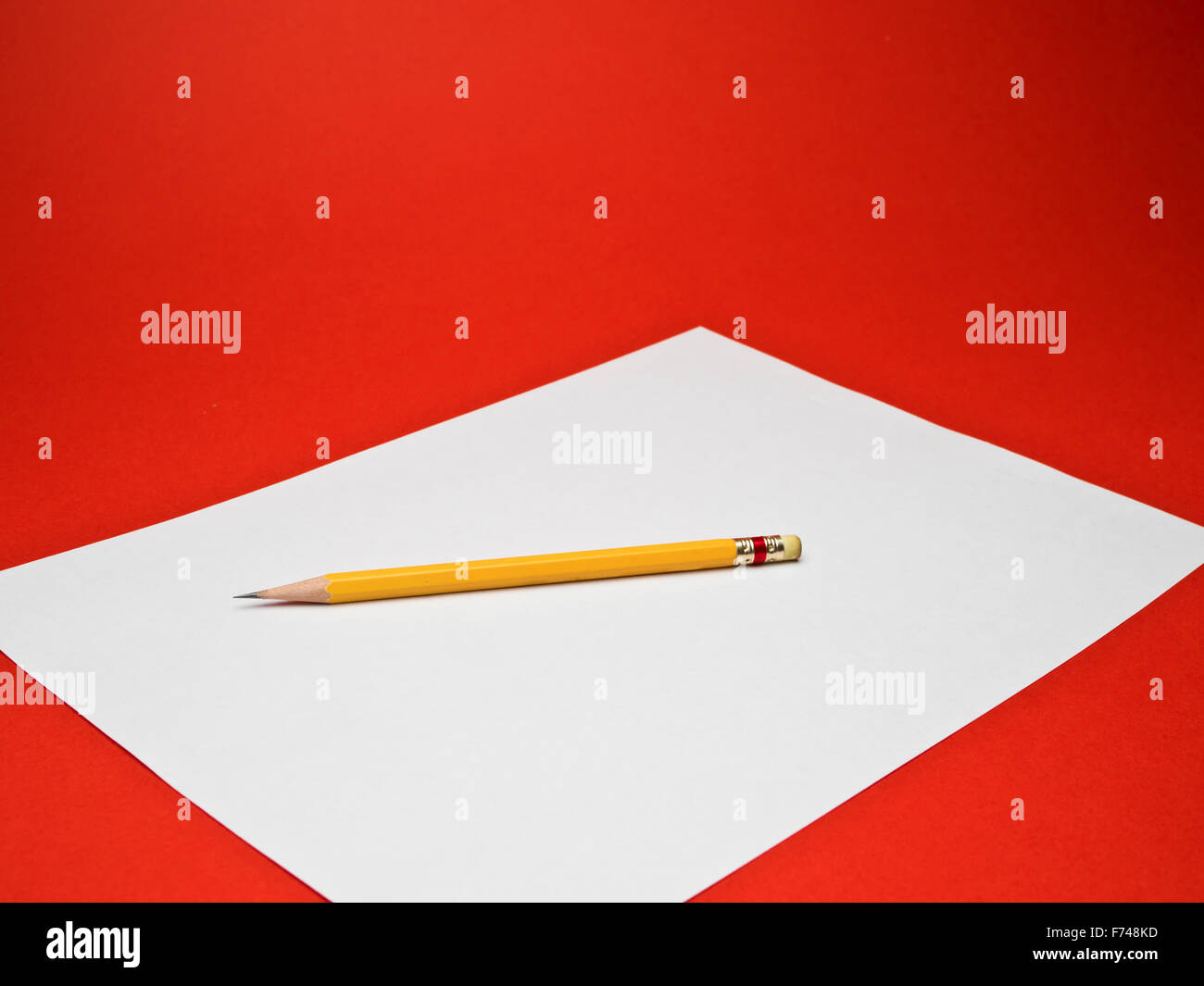 weißes Papier mit einem gelben Bleistift auf rotem Grund Stockfoto