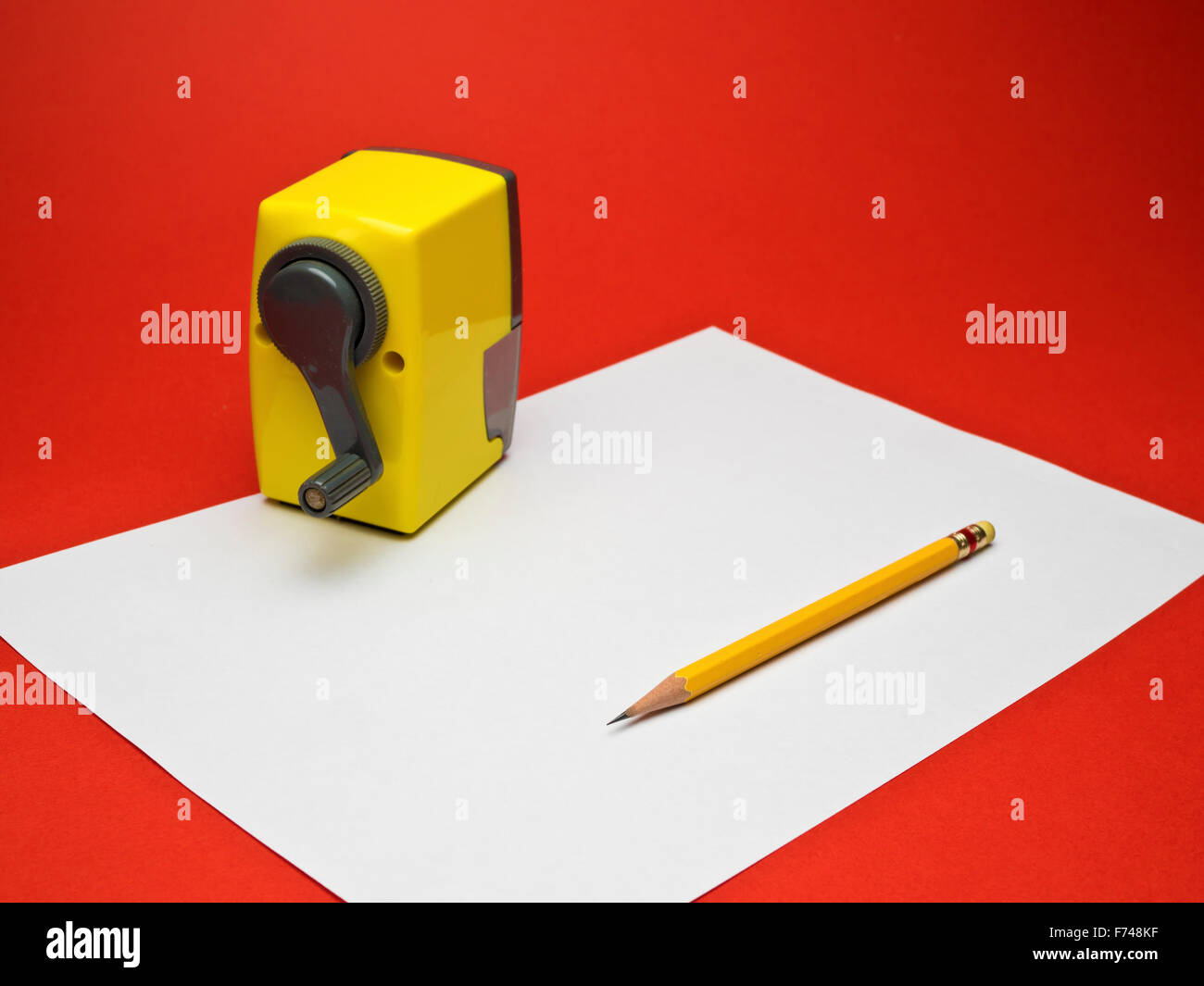 weißes Papier mit gelben Bleistift und spitzer auf rotem Grund Stockfoto