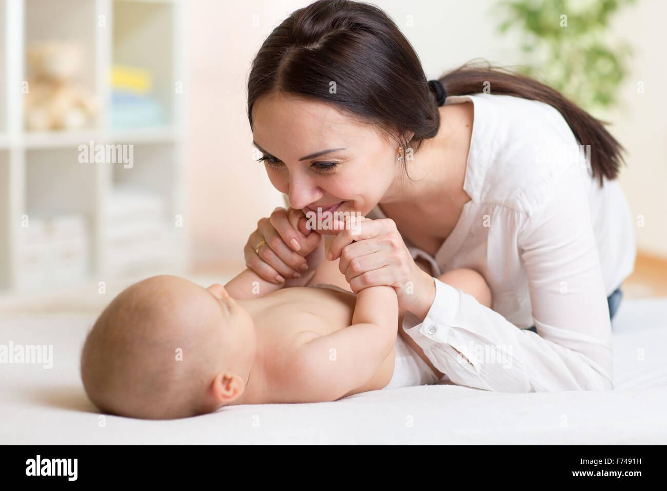 Glückliche Mutter mit ihrem Baby im Schlafzimmer spielen Stockfoto