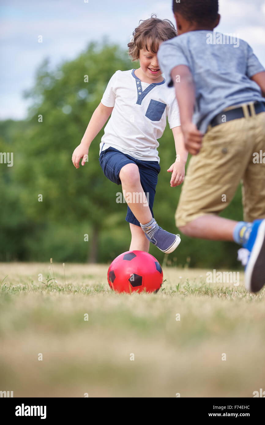 Zwei glückliche Kinder spielen Fußball im park Stockfoto