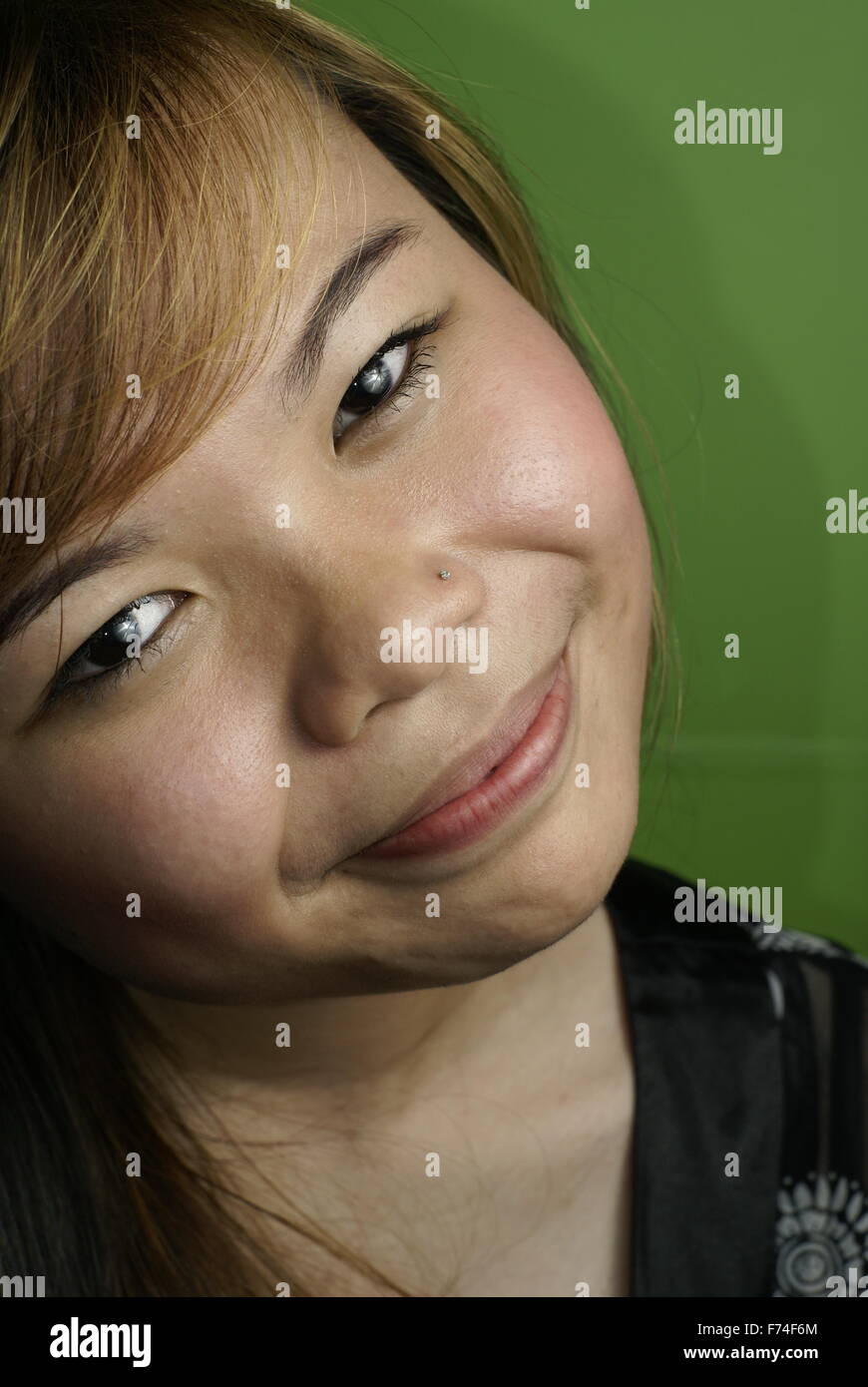 Lächelnde asiatische Dame auf grünem Hintergrund Stockfoto