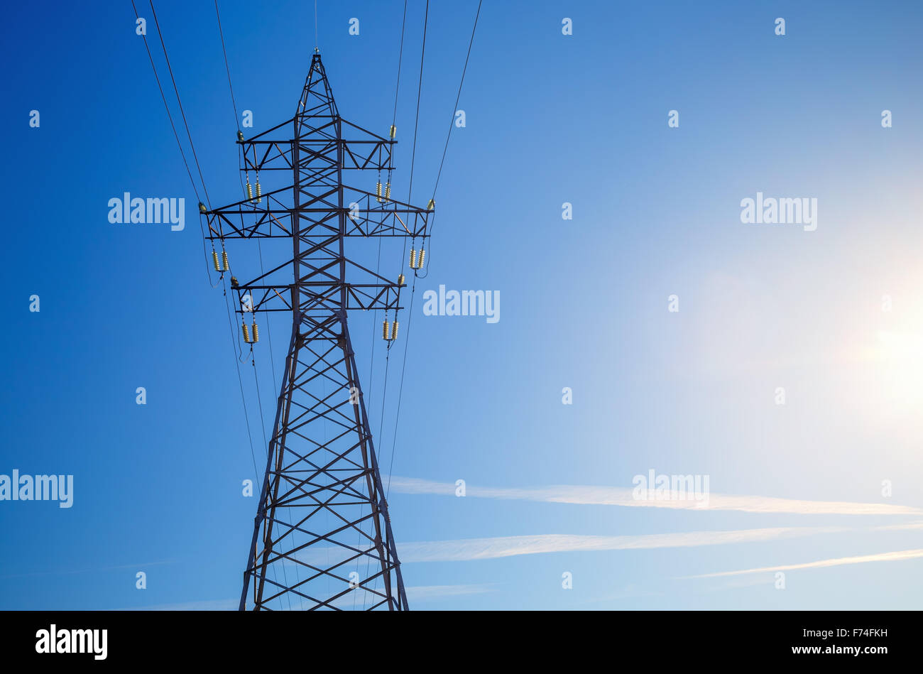 Strommast vor blauem Himmelshintergrund abhebt. Hochspannungs-Turm. Stockfoto
