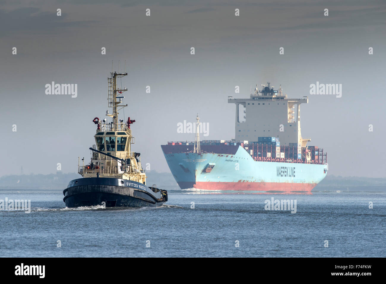 Der Schlepper Svitzer Bootle begleitet das Containerschiff Maersk Lota, wie sie flussaufwärts auf der Themse dampft. Stockfoto