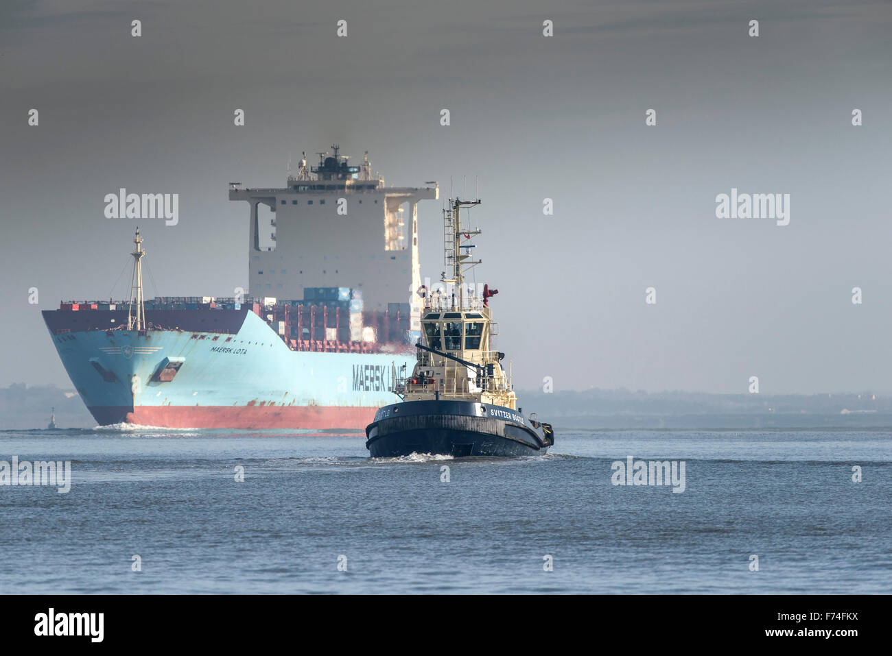 Der Schlepper Svitzer Bootle begleitet das Containerschiff Maersk Lota, wie sie flussaufwärts auf der Themse dampft. Stockfoto