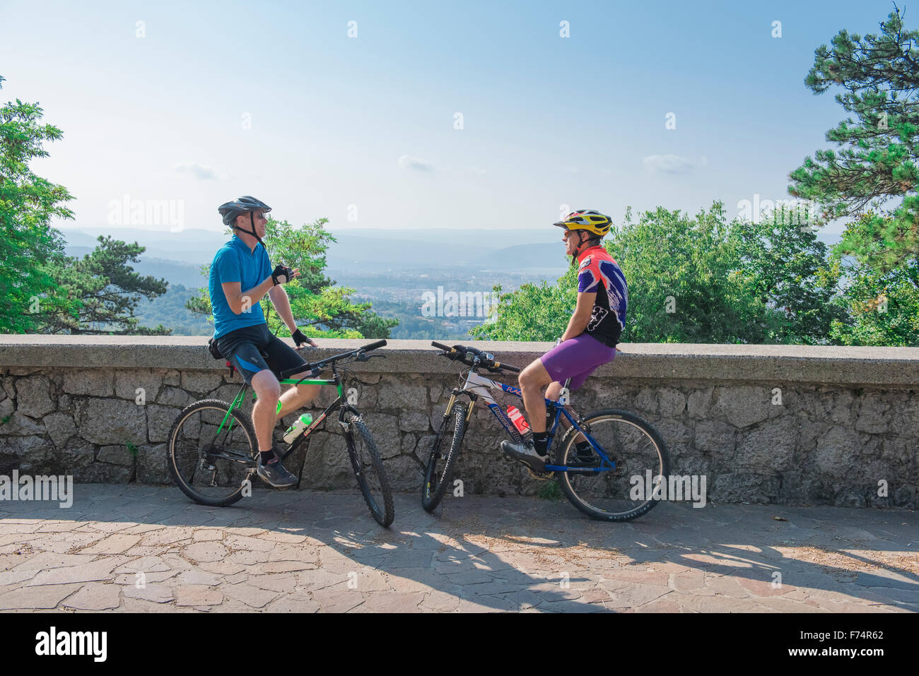 Sprechende Radfahrer, Blick auf zwei männliche Radfahrer, die sich auf einer Straße mit Blick auf die Adria westlich von Triest, Italien, ruhten. Stockfoto