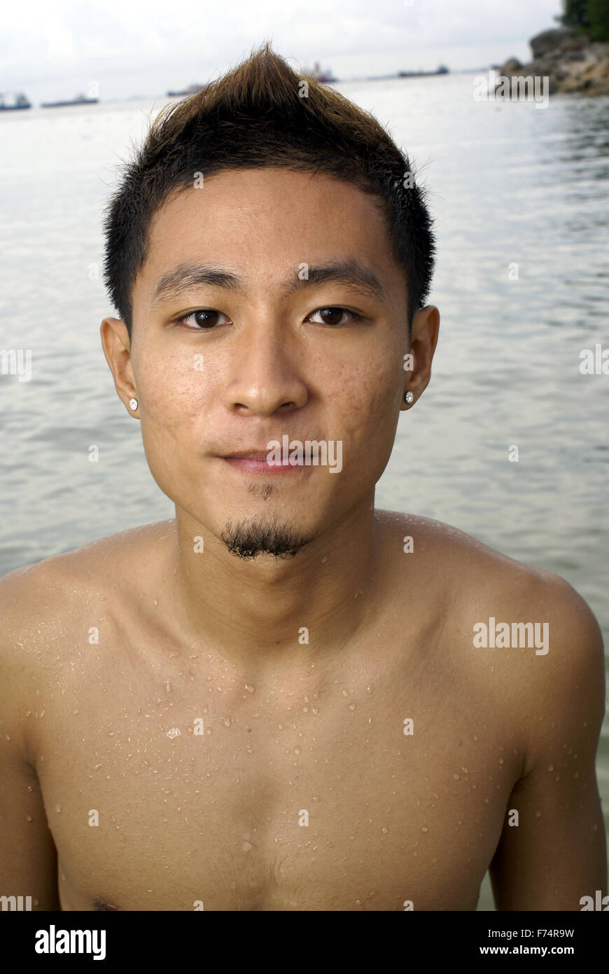 Chinesische asiatische Mann am Strand mit Ohrringen Stockfoto