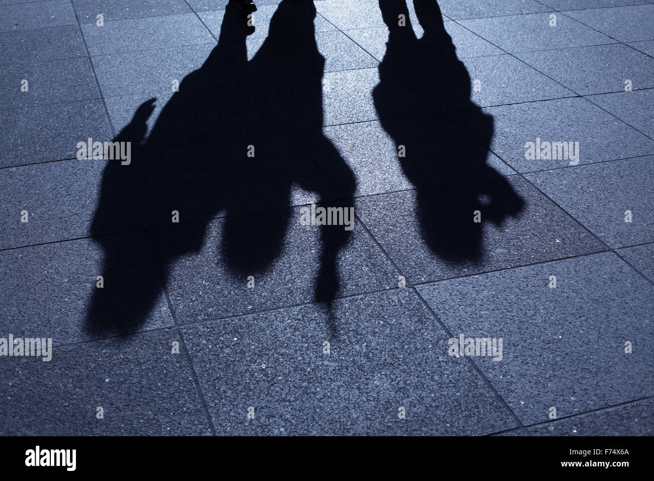 Blaue Nacht Schatten und Silhouetten von bedrohlichen Bande von Menschen voran auf dem Gehsteig Stockfoto