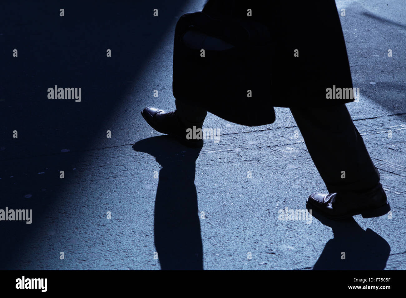 Blaue Nacht Schatten und Silhouette eines unkenntlich Mannes hinunter eine Stadt Bürgersteig mit dem Aktenkoffer Stockfoto