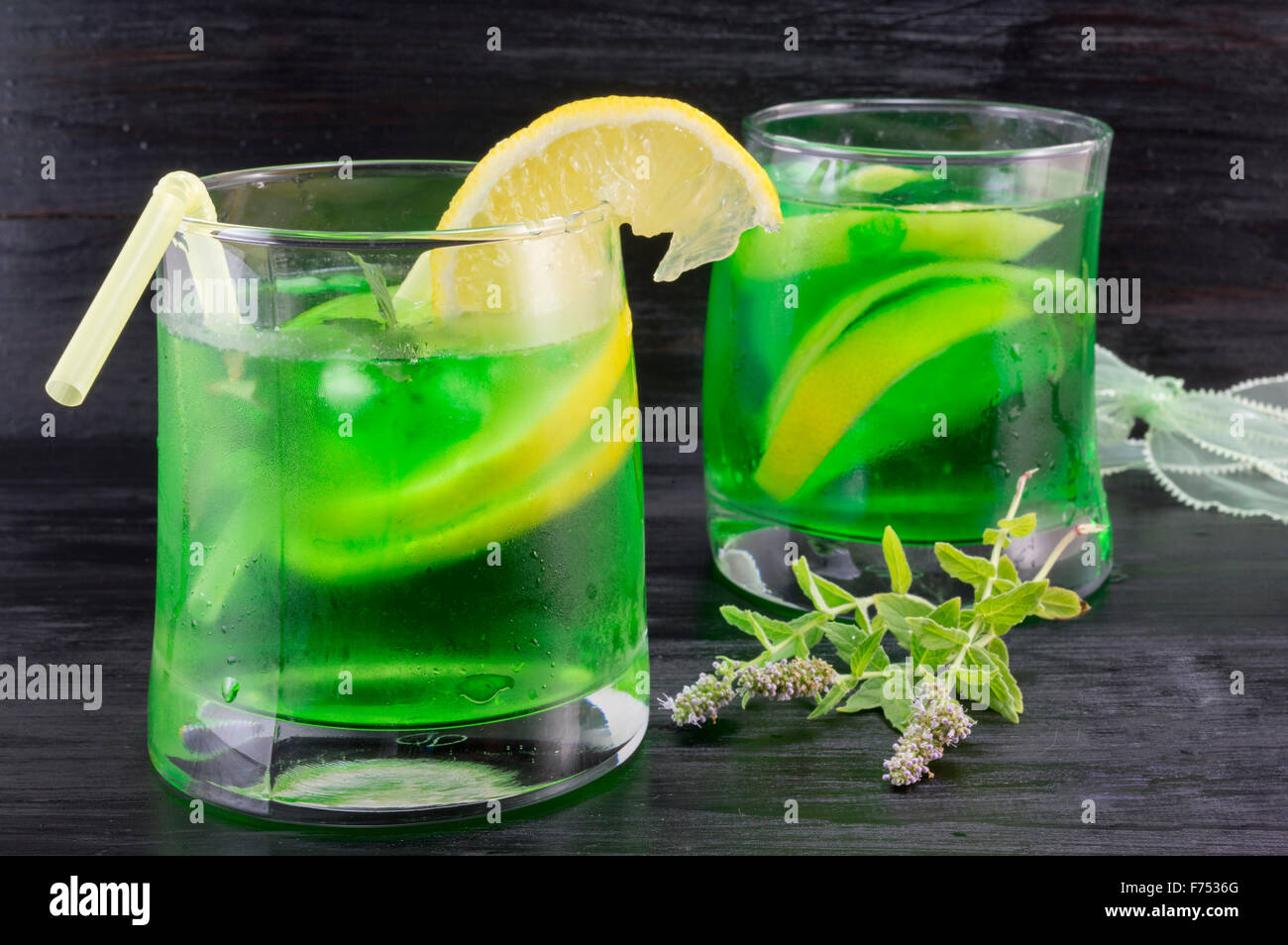 Hausgemachtes Mojito cocktail in einem gebogenem Glas und frischer Minze Pflanze auf dunklen Hintergrund Stockfoto