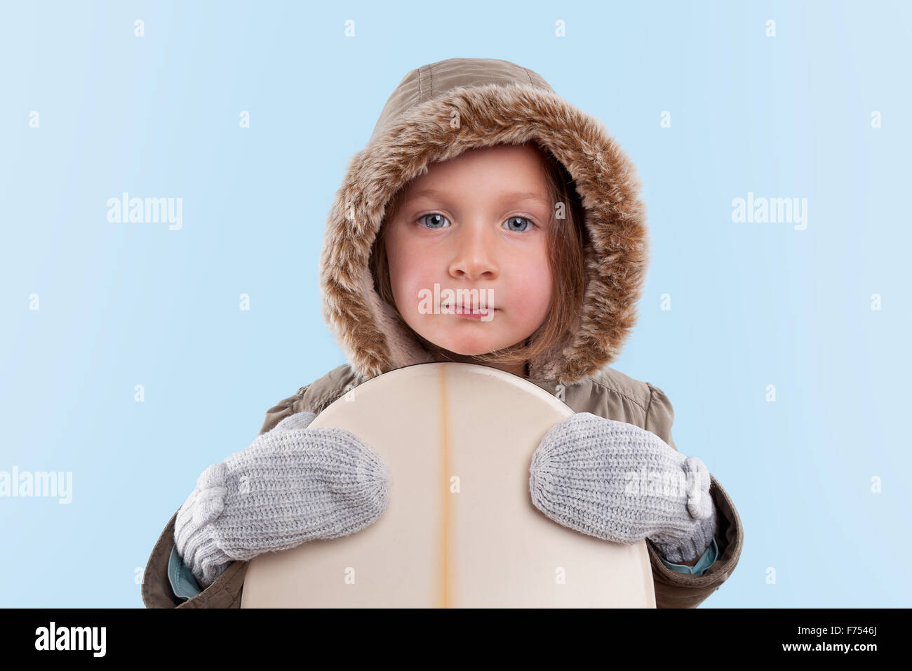 Kleinen Snowboarder. Niedliche kleine Mädchen mit Snowboard gegen hellblauen Hintergrund. Stockfoto