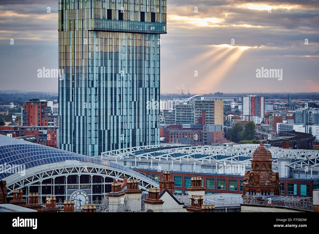 Manchester Skyline zeigen sich die Dächer der Spiele g-Mex zentrale Betham Turm Lichtschacht Strahlen durch die Wolken Sonnenuntergang Dämmerung niedrigen ligh Stockfoto