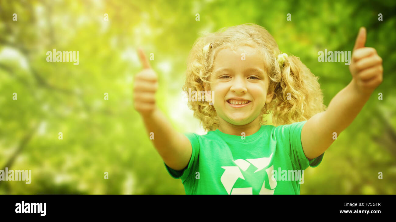 Zusammengesetztes Bild von glücklichen kleinen Mädchen in grün mit Daumen nach oben Stockfoto