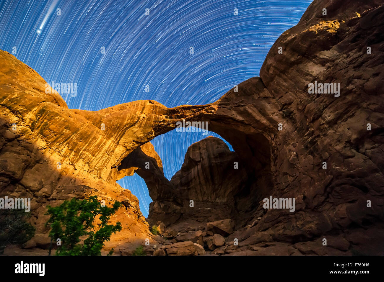 Zirkumpolare Sterne Wanderwege Spinnen hinter Double Arch im Arches-Nationalpark, Utah, als die abnehmenden Crescent Moon Lights der Bögen Stockfoto