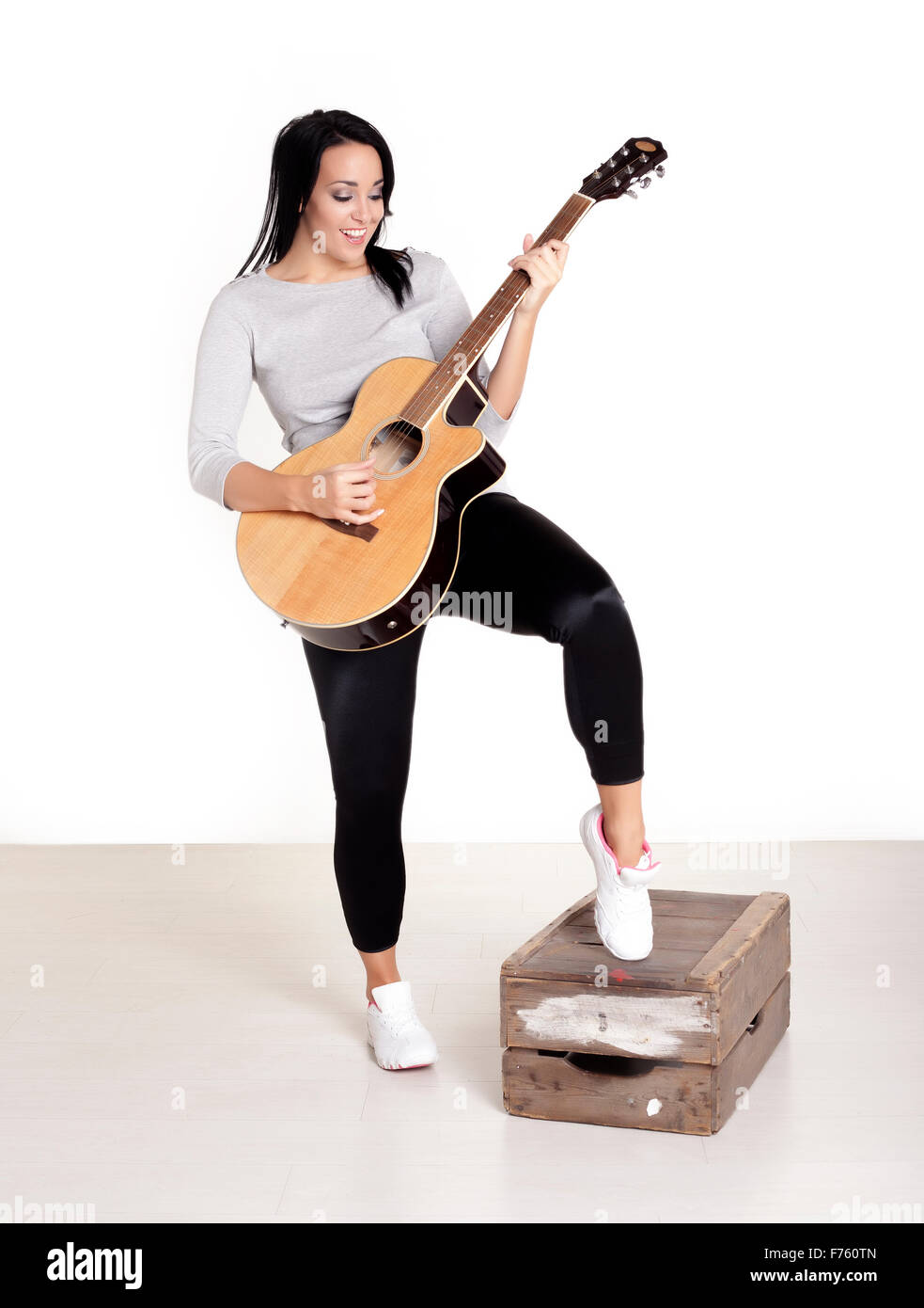 Junge weibliche Busker sitzen auf einem hölzernen Kasten ihrer Gitarre um Geld zu spielen. Stockfoto