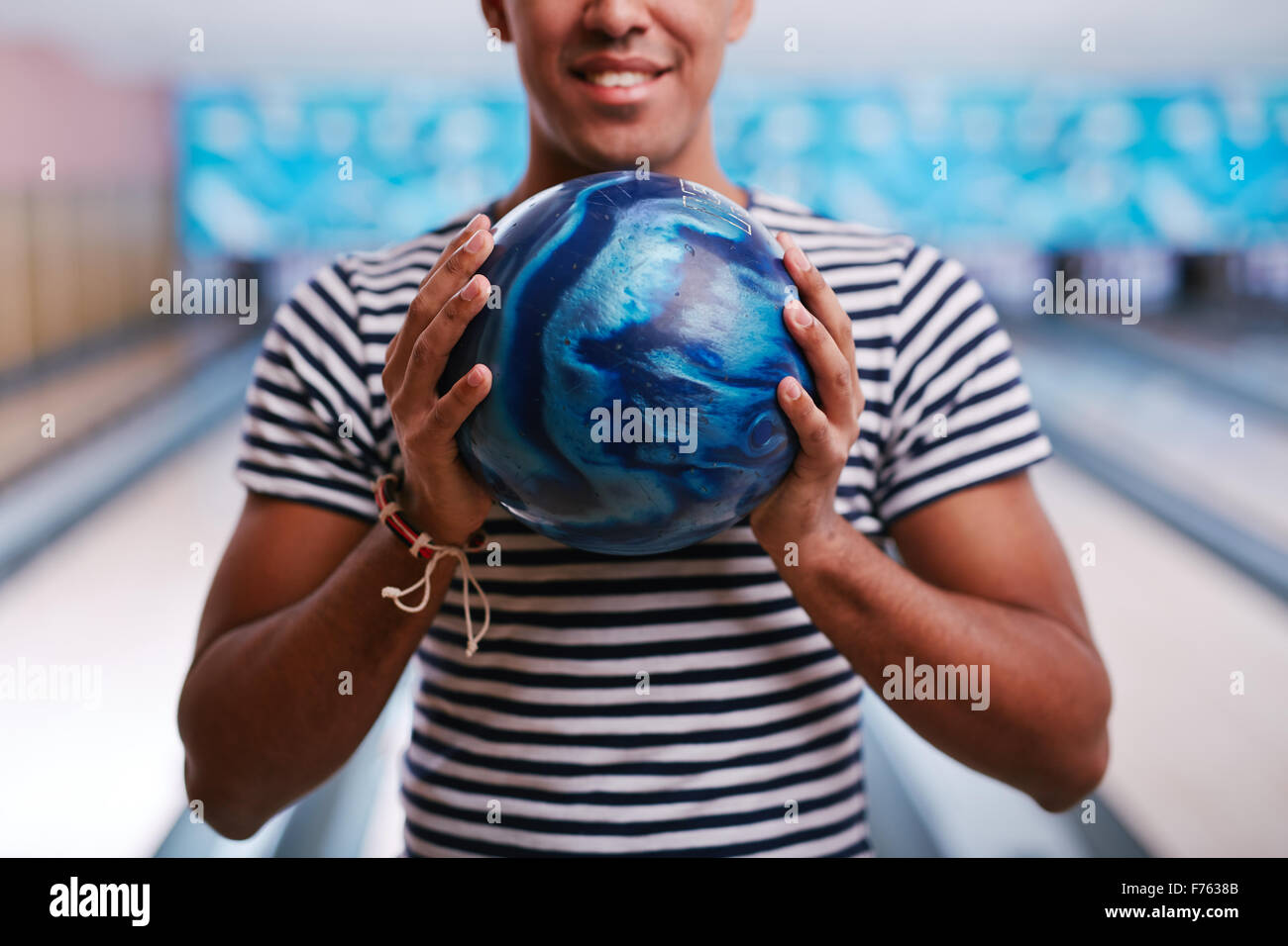 Junger Mann mit Bowling-Kugel in den Händen Stockfoto