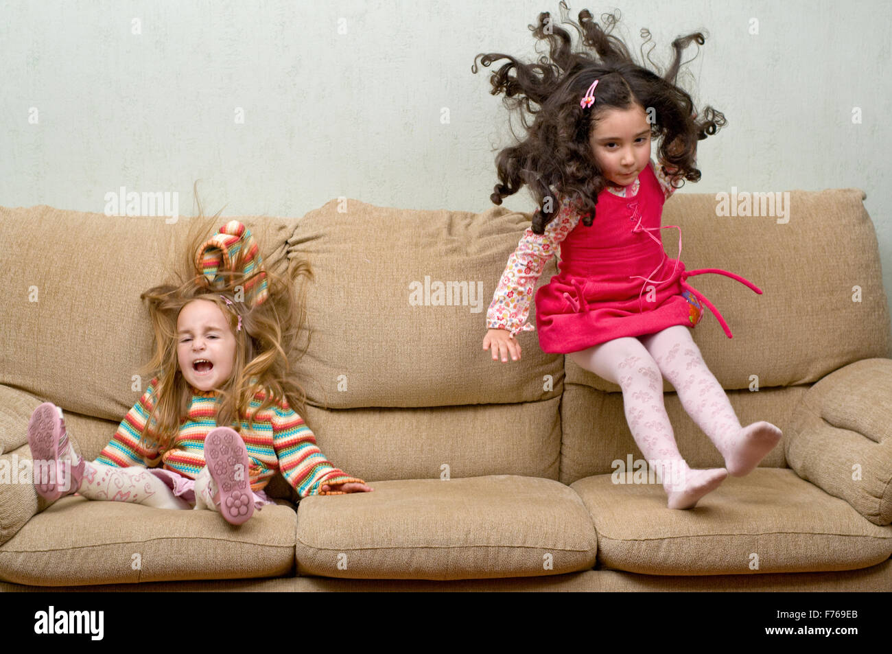 zwei kleine Mädchen springen auf sofa Stockfoto