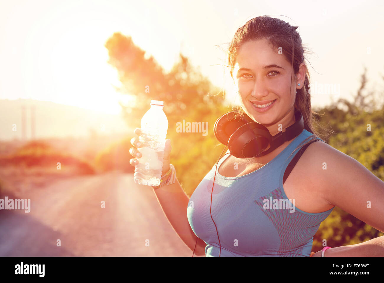 Schöne Mädchen Jogger im freien Trinkwasser bei Sonnenuntergang Stockfoto