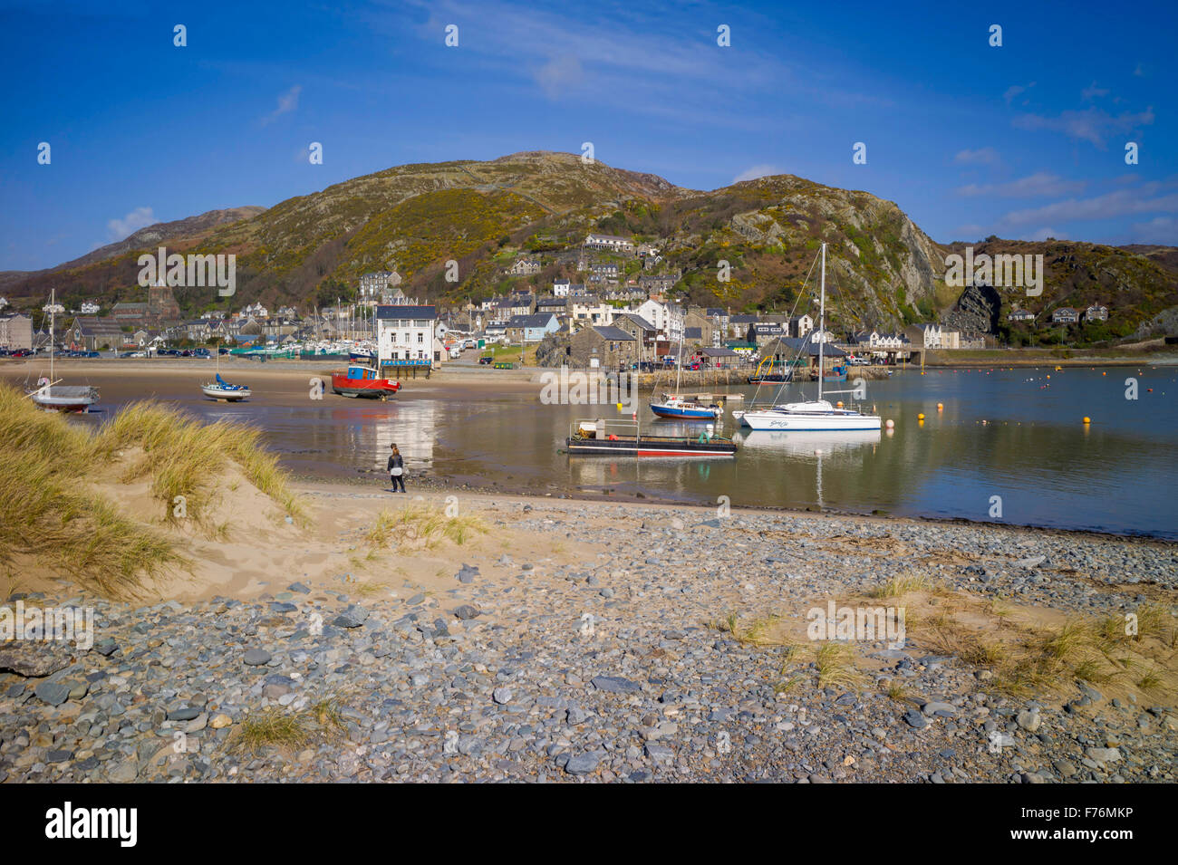 Ein Blick über den Kiesstrand in Richtung Barmouth Stadt und den Hafen mit kleinen Häusern verstreut auf die umliegenden Hügel. Stockfoto