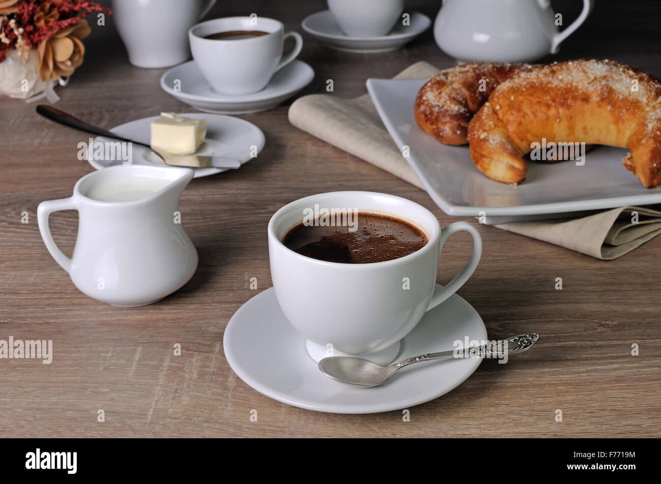 Tasse Kaffee mit Croissants, Butter und Milch auf dem Tisch Stockfoto