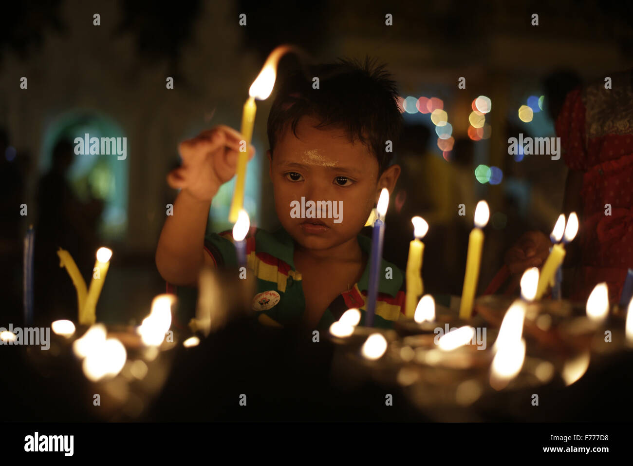 (151126)--YANGON, 26. November 2015 (Xinhua)--A Kind Lichter Kerzen auf Myanmars Tazaungdaing Volksfest an der Shwedagon-Pagode in Yangon, Myanmar, 26. November 2015. Das Tazaungdaing-Festival, auch bekannt als das Festival of Lights am Tag des Vollmonds im achten Monat des traditionellen Myanmar Kalenders fällt in Myanmar als nationaler Feiertag gefeiert und markiert das Ende der Regenzeit. (Xinhua/U Aung) Stockfoto