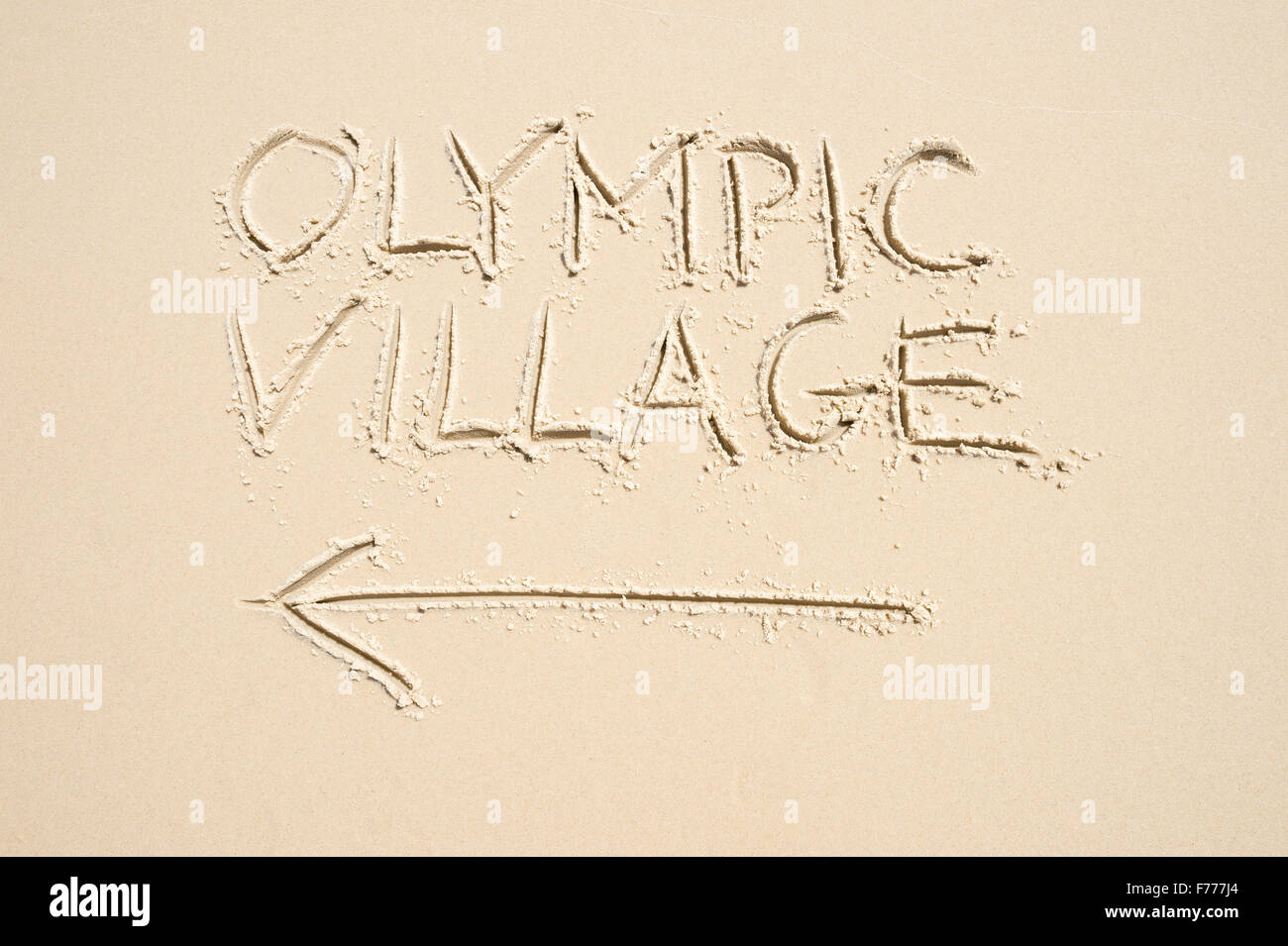 RIO DE JANEIRO, Brasilien - 10. November 2015: Handschriftliche Nachricht mit Pfeil weisen den Weg zu Olympischen Dorf in Sand geschrieben. Stockfoto