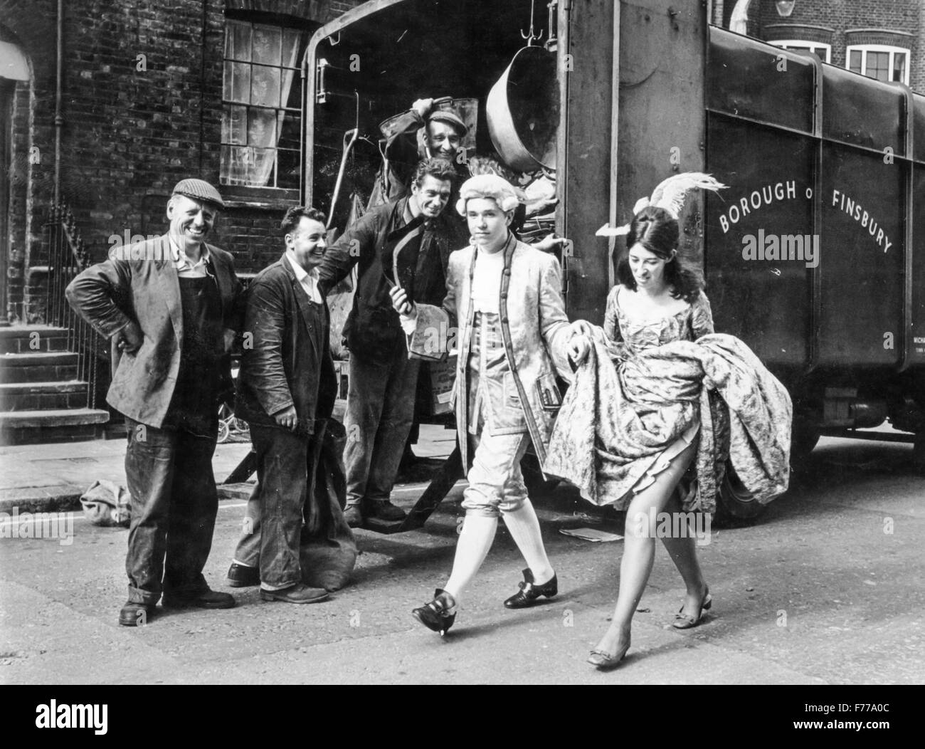 ein paar von maskierten Jugendlichen übergeben vor einer Gruppe von Arbeitnehmern, London, England, uk. 1967 Stockfoto