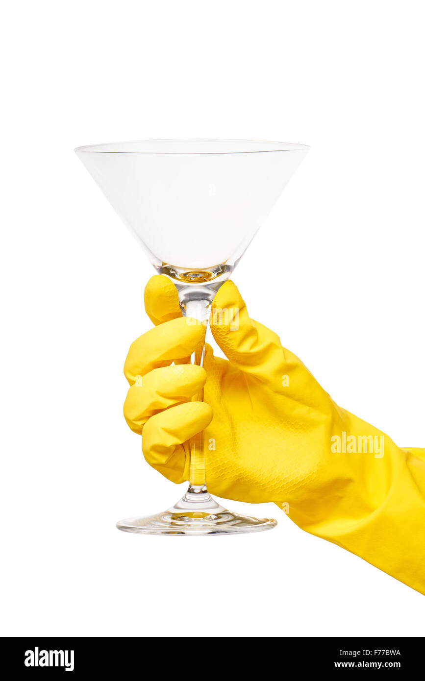 Nahaufnahme des weiblichen Hand in gelben schützende Gummihandschuh hält sauber transparent Martiniglas vor weißem Hintergrund. Stockfoto