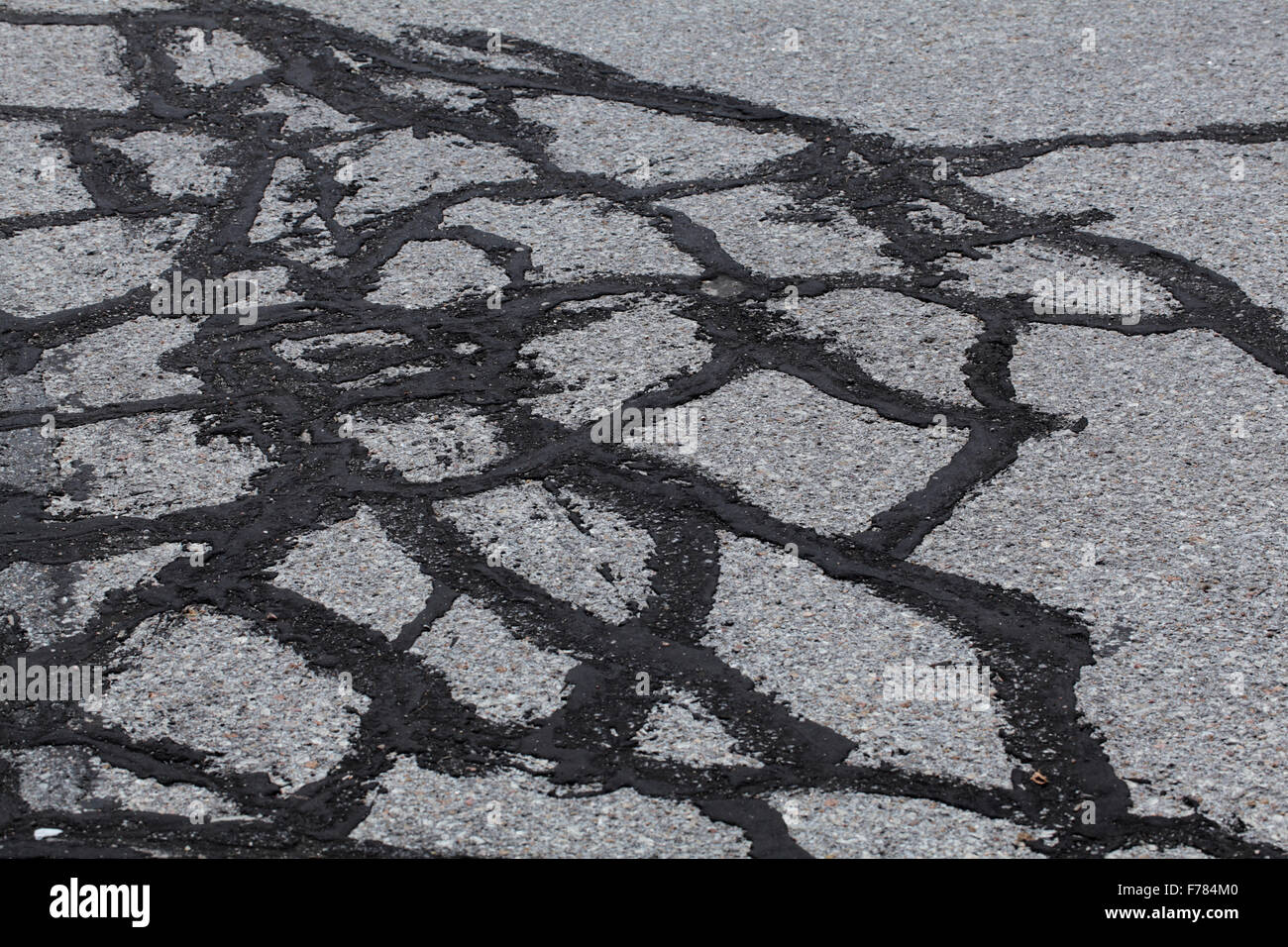 Alten Asphalt, zeigt Risse geflickt mit Teer. Stockfoto