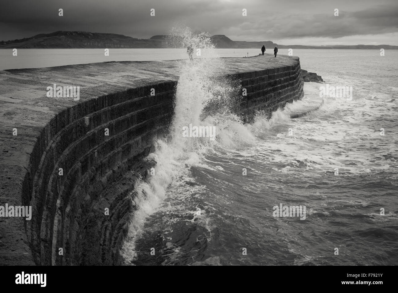 Menschen ausweichen eine brechende Welle auf der Seite der Cobb bei Lyme Regis Stockfoto