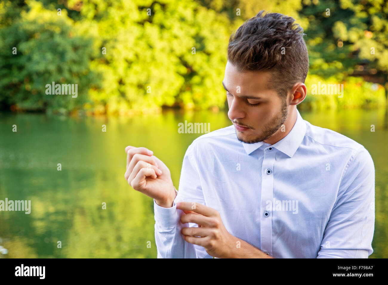 Porträt des kontemplativen leichte Braunhaarige junge Mann trägt weißes Hemd neben malerischen Fluss oder See, Blick auf Hemd cu Stockfoto