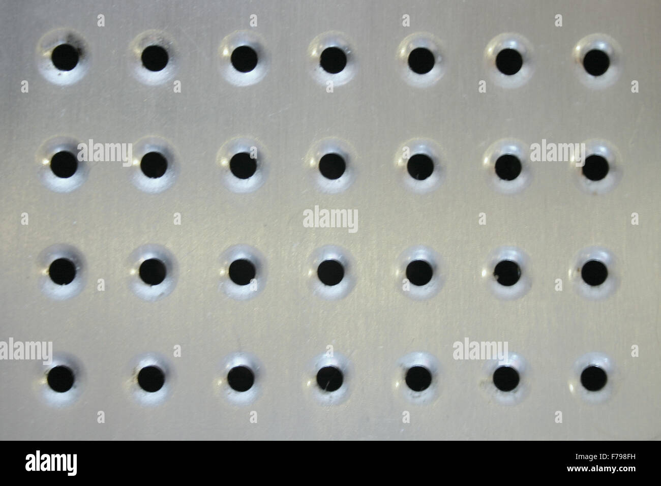 glänzende gebürsteten Metalloberfläche mit Löchern Stockfoto