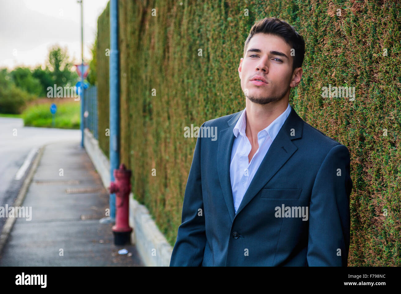 Hübscher junger Mann in eleganten Business-Anzug stehen im Freien in Straße Blick in die Kamera Stockfoto