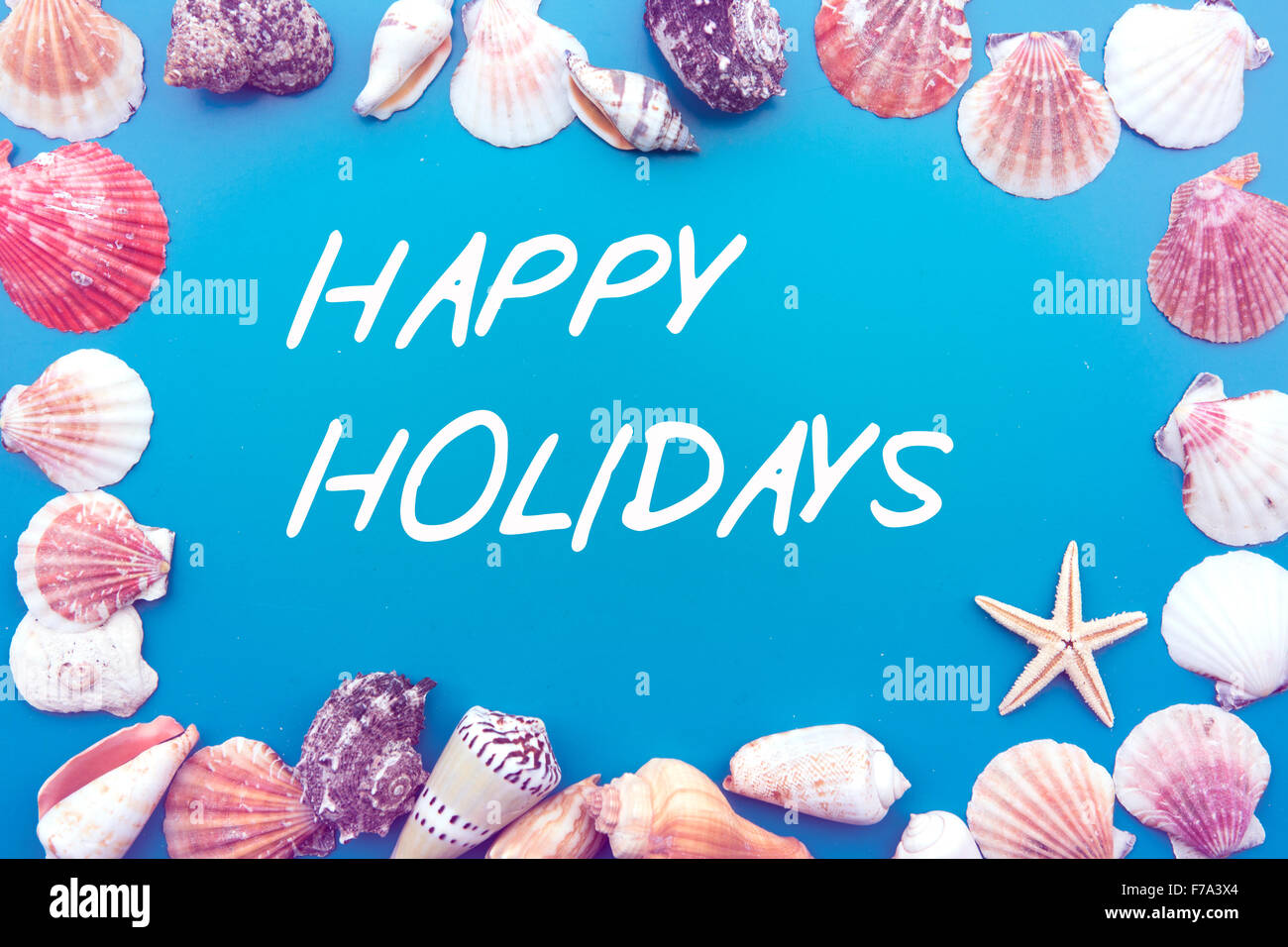 "Happy Holidays" geschrieben auf blauem Hintergrund mit Muscheln Stockfoto
