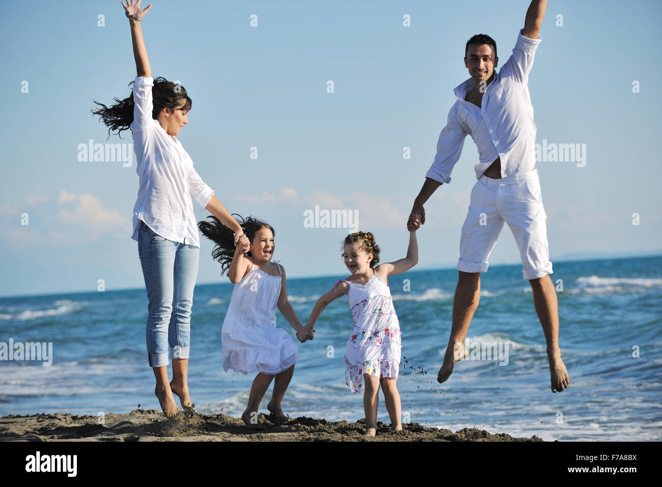 glückliche junge Familie in weißer Kleidung viel Spaß im Urlaub am schönen Strand